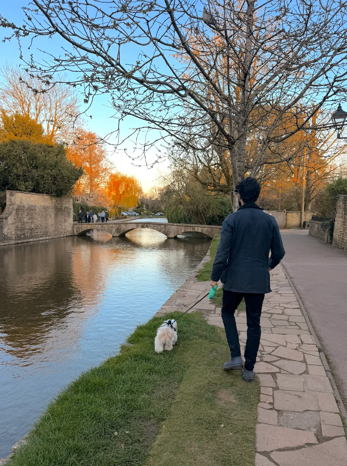 Shamil walking his dog beside the river in Bourton-on-the-Water at golden hour